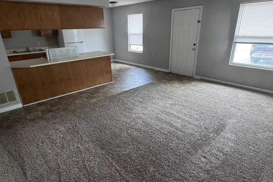 Living room of the 3 bedroom home, carpeted with windows to the front yard