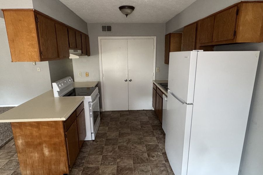 Kitchen with full size refrigerator, range, and wood cabinets